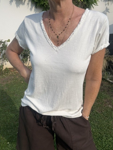 Top femme à manches courtes avec col V et finitions franges, style bohème chic, idéal pour une tenue estivale et élégante et décontractée.
