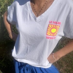 T-shirt femme Soleil blanc à col V avec imprimé coloré fluo Soleil sur la poitrine. Matière coton, manches courtes et style estival décontracté.
