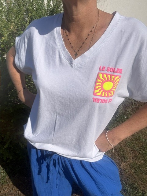 T-shirt femme Soleil blanc à col V avec imprimé coloré fluo Soleil sur la poitrine. Matière coton, manches courtes et style estival décontracté.