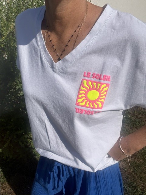 T-shirt femme Soleil blanc à col V avec imprimé coloré fluo Soleil sur la poitrine. Matière coton, manches courtes et style estival décontracté.