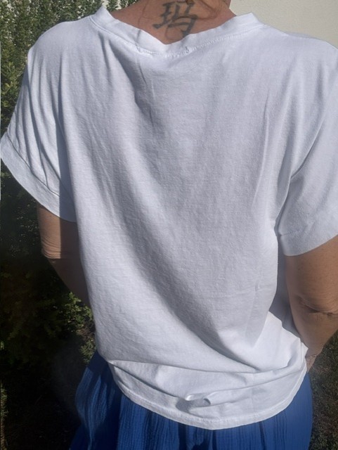 T-shirt femme Soleil blanc à col V avec imprimé coloré fluo Soleil sur la poitrine. Matière coton, manches courtes et style estival décontracté.