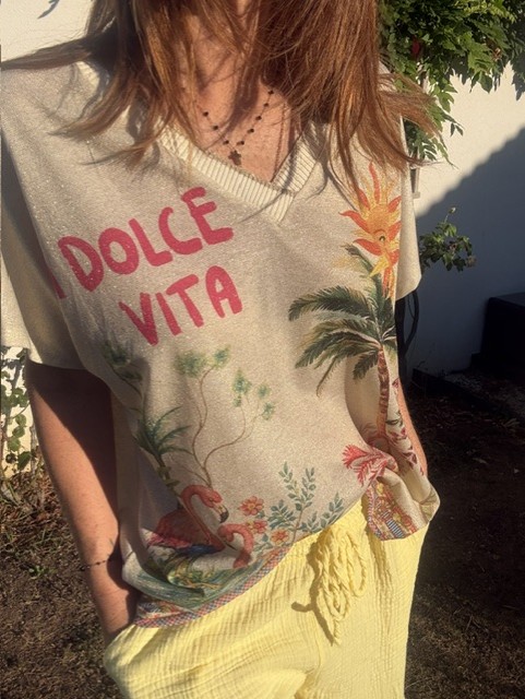 Top femme La Dolce Vita en maille légère avec lurex, col V, imprimé soleil, palmiers, fruits et inscription colorée. Haut estival chic et décontracté.