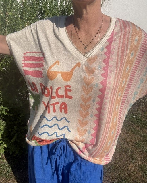 Top femme La Dolce Vita en maille légère avec lurex, col V, imprimé soleil, palmiers, fruits et inscription colorée. Haut estival chic et décontracté.